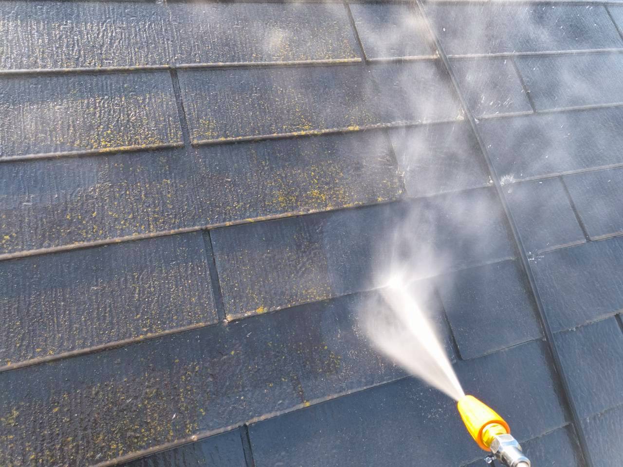 苔が付着したスレート屋根を高圧洗浄中